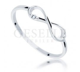 Delikatny pierścionek w kształcie symbolu nieskończoności z białego złota z lśniącym brylantem o masie 0.01 ct
